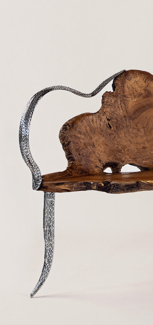 Eine Seitenansicht einer einzigartigen Teakholz-Bank mit geschwungenen, metallischen Beinen und einer charakteristischen, natürlich geformten Holzoberfläche, die durch Hohlräume und natürliche Holzmaserung akzentuiert wird