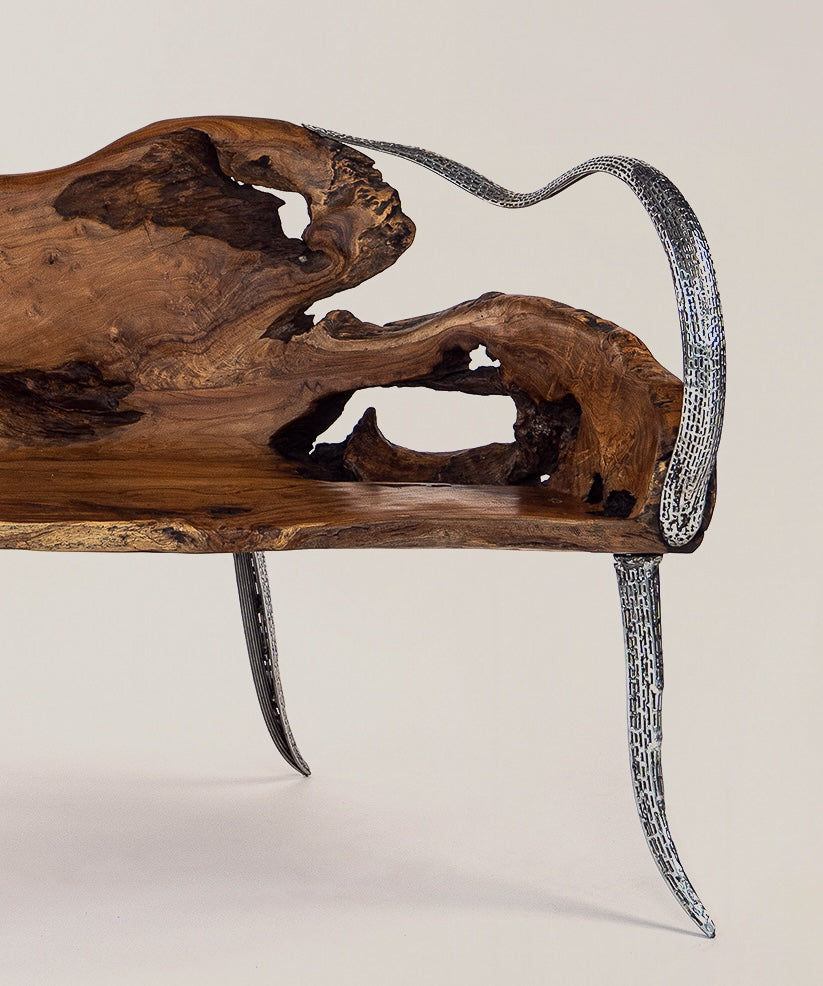 Eine Seitenansicht einer einzigartigen Teakholz-Bank mit geschwungenen, metallischen Beinen und einer charakteristischen, natürlich geformten Holzoberfläche, die durch Hohlräume und natürliche Holzmaserung akzentuiert wird