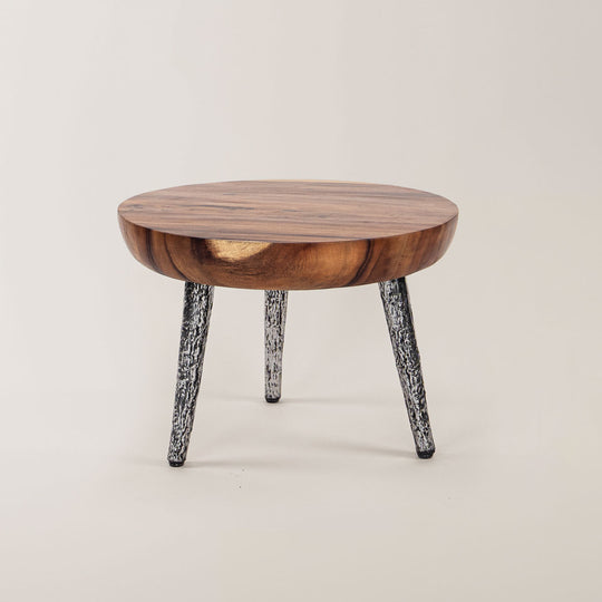 Stilvoller Suar-Elegance Rundtisch mit glatter, natürlicher Holzplatte und unkonventionellen, metallisch gemusterten Beinen, ideal für ein minimalistisches und modernes Zuhause.