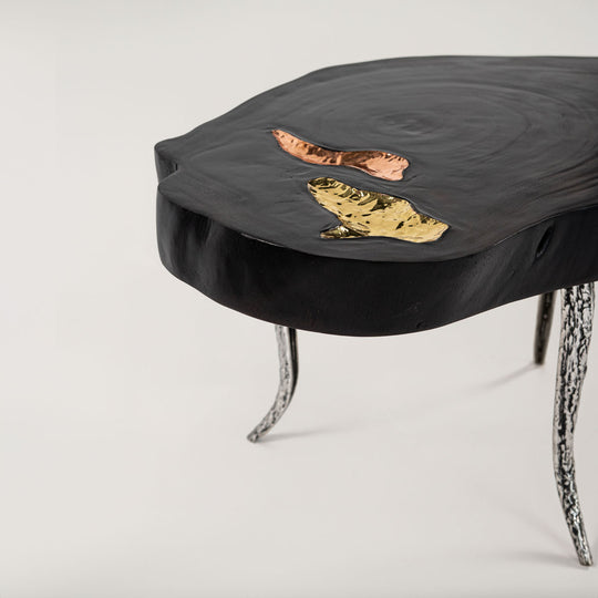 Moderner SuarAurumCopper Beistelltisch in Schwarz mit einzigartigen, eingelassenen Details aus Kupfer und Gold, getragen von geschwungenen, metallisch gemusterten Beinen, die einen auffälligen Kontrast bilden.