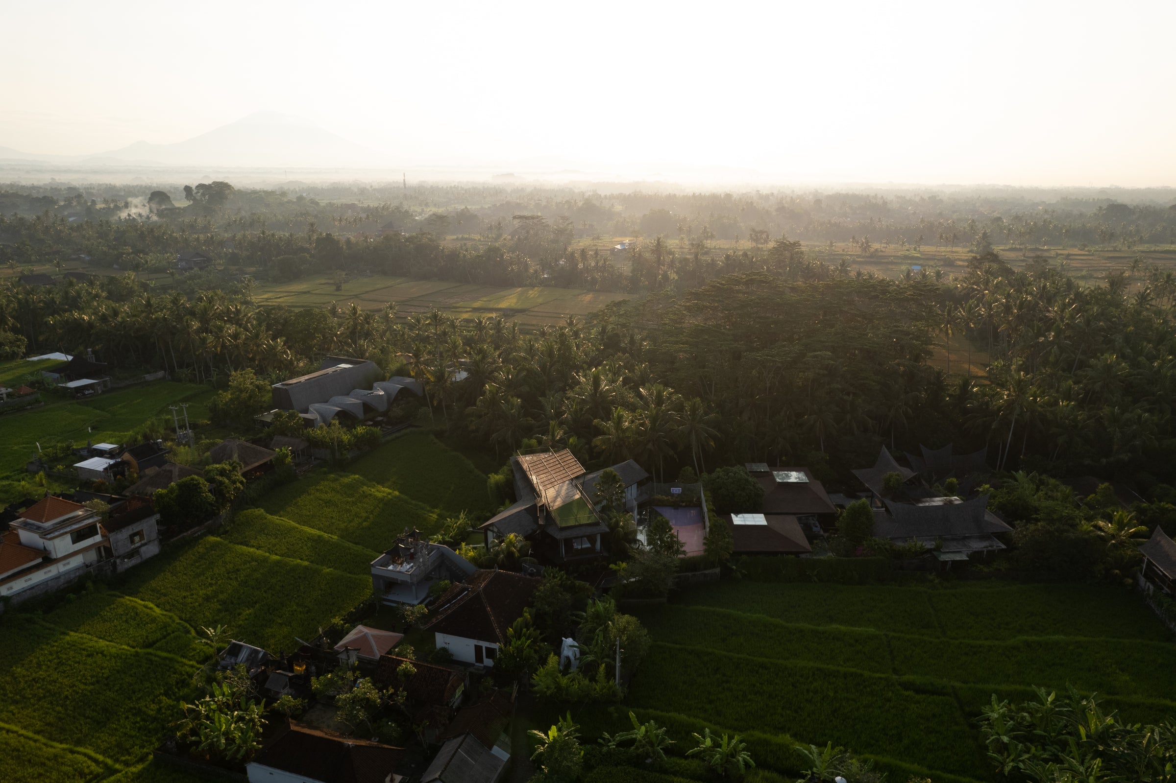 Luftaufnahme indonesisches Dorf in der Nähe der Produktionsstätten von INDOO. Teakholz - Wälder und Blick auf den Vulkan